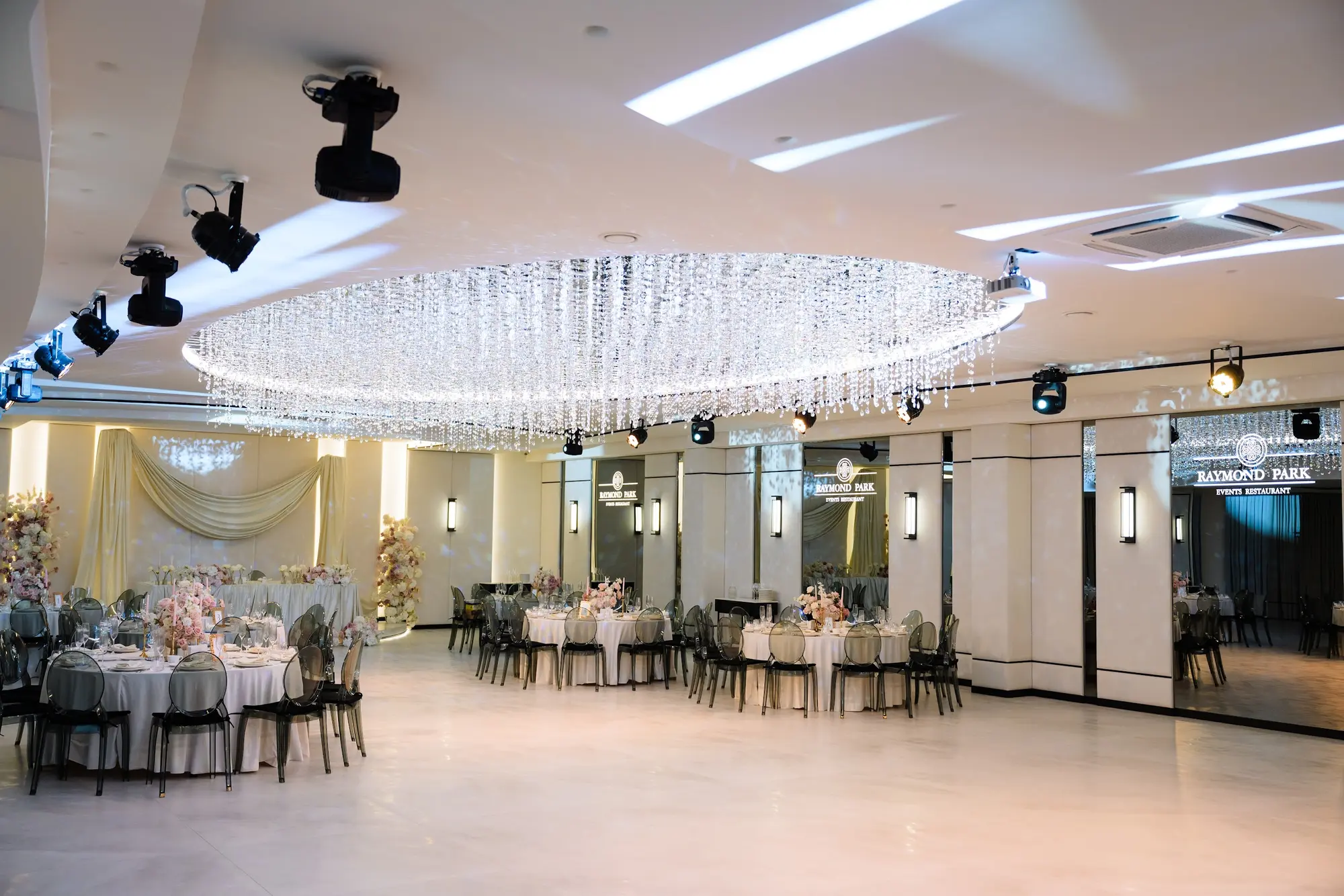 Sala Noir aranjată cu mese rotunde, sub candelabrul de cristal