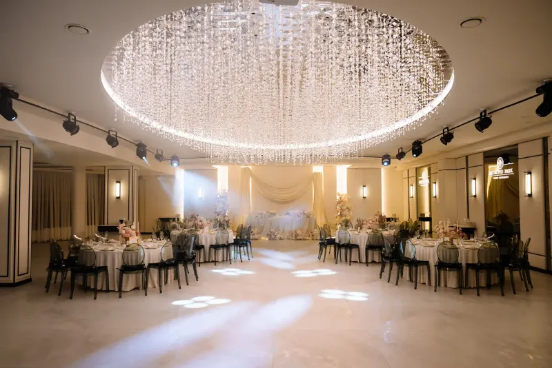 Sala Noir sub candelabrul rotund de cristal, cu mese rotunde și scaune transparente