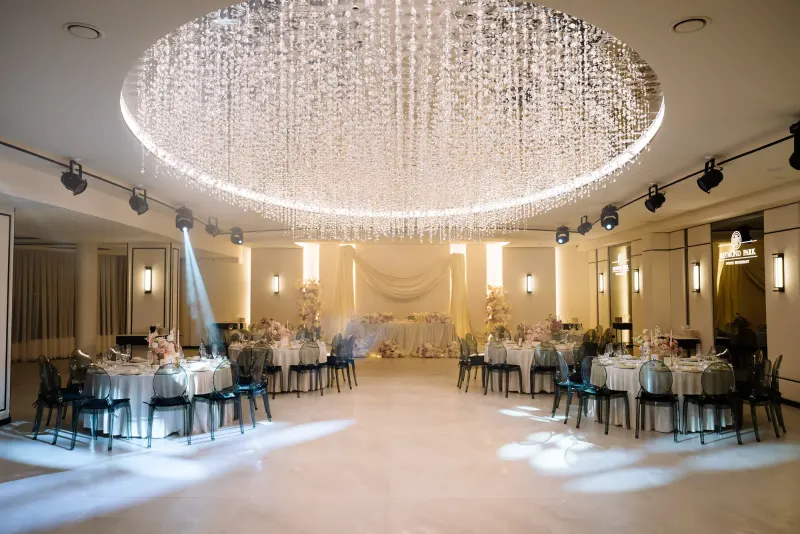Sala Noir sub candelabrul rotund de cristal, cu mese rotunde și scaune transparente