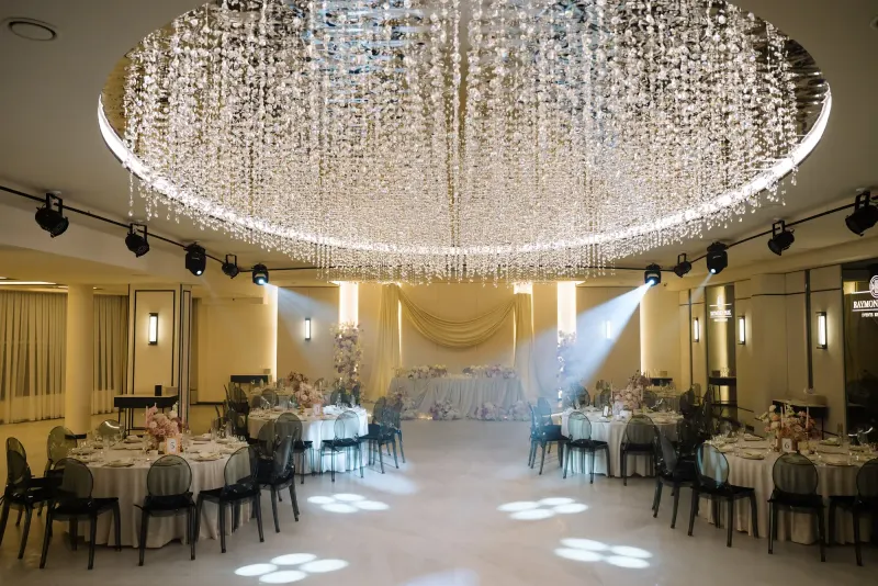 Sala Noir sub candelabrul rotund de cristal, cu mese rotunde și scaune transparente