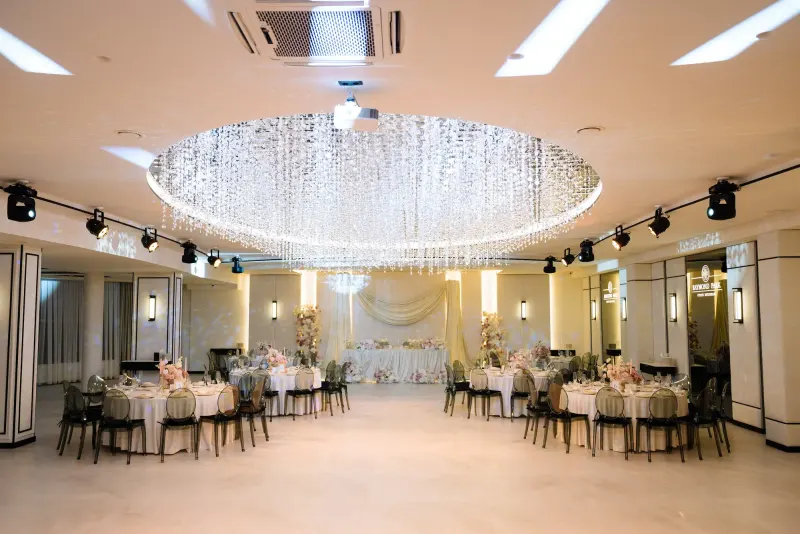 Sala Noir sub candelabrul rotund de cristal, cu mese rotunde și scaune transparente