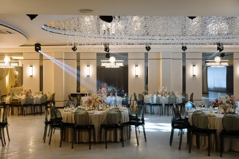 Sala Noir sub candelabrul rotund de cristal, cu mese rotunde și scaune transparente