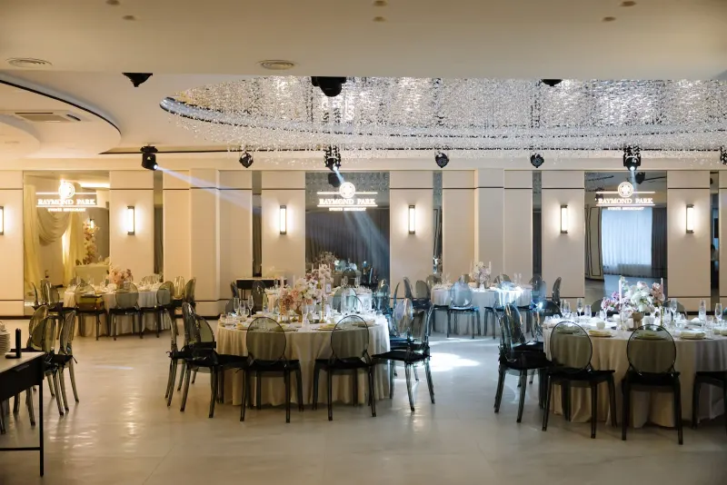 Sala Noir sub candelabrul rotund de cristal, cu mese rotunde și scaune transparente