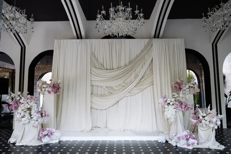 Arcada de ceremonie din sala Noir, cu draperii crem, flori și candelabru