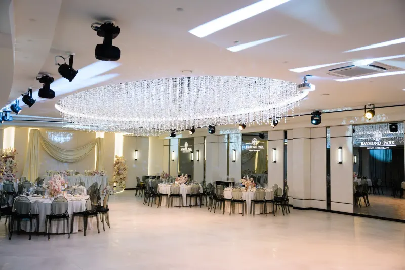 Sala Noir sub candelabrul rotund de cristal, cu mese rotunde și scaune transparente